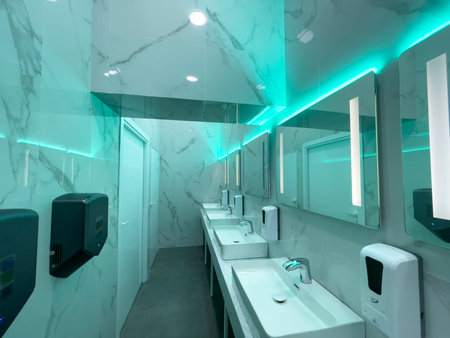 Contemporary restroom featuring marble walls, multiple sinks, mirrors, and neon lighting. The design...