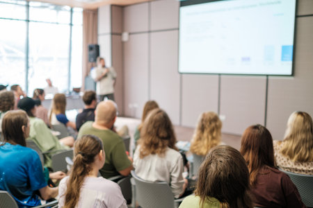Speaker delivering presentation to attentive audience in modern conference setting. Engaged...