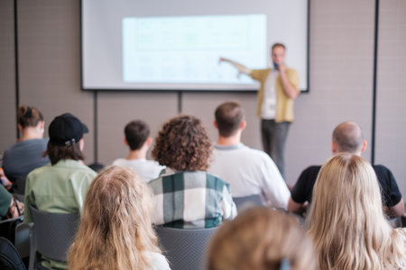 Group of people attending presentation in conference setting, focusing on speaker and projection screen. Engaging learning environment with diverse audience.の写真素材