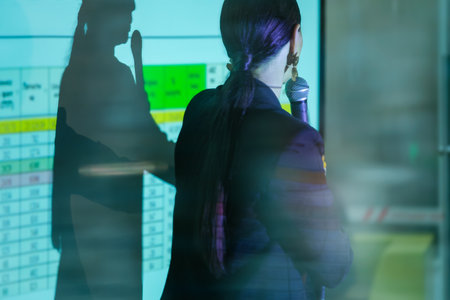 Business professional delivering a presentation using a microphone, highlighting financial data on a...