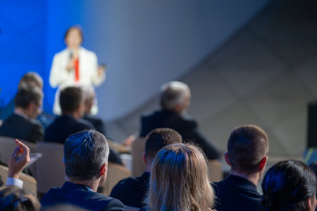 Business professional presenting at a conference with attendees listening and participating. Engaged and attentive audience in a corporate seminar.の写真素材
