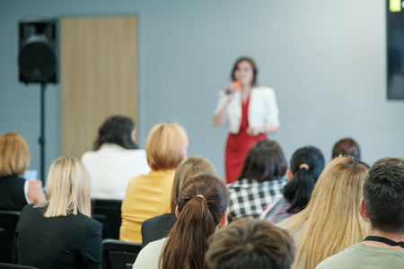 A woman presenting to a business audience in a conference room. Attendees sitting and listening attentively.の写真素材