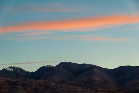 Serene Altai Mountains captured in autumn, featuring a picturesque sunset sky with vibrant hues of pink and blue in the background.の写真素材