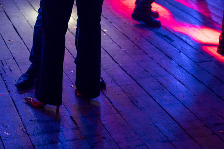 Image of a club dance floor under vibrant lights showing feet of people dancing energetically, capturing nightlife atmosphere.の写真素材