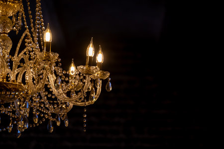 Sophisticated crystal chandelier with glowing lights shining against a dark background, creating ambiance of luxury and elegance, perfect for upscale interiors.の写真素材