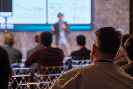 Participants focus on presenter during professional conference with projections on screen.の写真素材