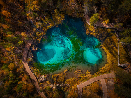 Aerial view of Geyser Lake nestled in vibrant autumn forest. Turquoise waters create mesmerizing circular patterns.の写真素材