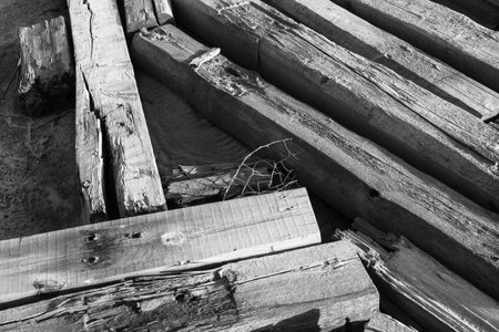 Detailed view of old wooden beams showing texture and grain in monochrome tones, creating a rustic...