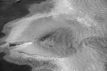 Aerial view showcasing textured, rugged salt formations in monochrome tones, creating abstract...