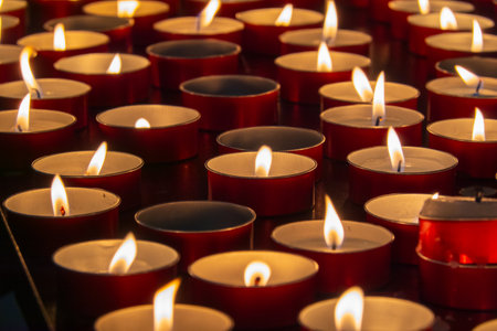 Rows of tea light candles in red holders glowing warmly, evoking peaceful, tranquil ambiance perfect for serene settings or special moments.の写真素材