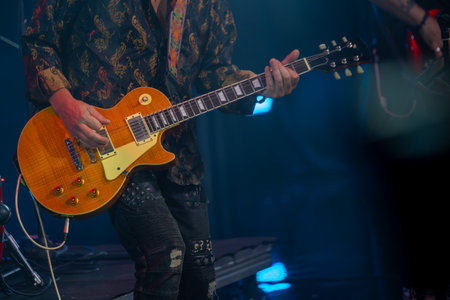 Musician passionately playing electric guitar during live performance. Vibrant atmosphere at concert with focus on instrument and musicians attire.の写真素材