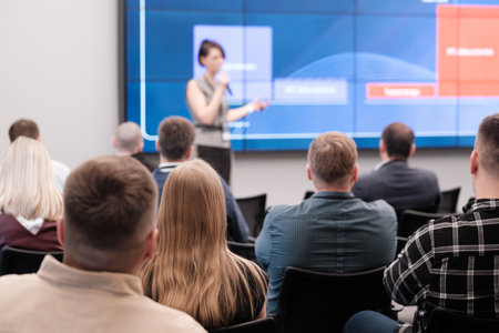 Speaker delivers engaging presentation in front of attentive audience, highlighting key points on large screen.の写真素材