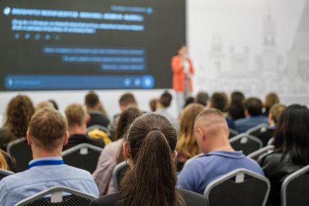 People gathered in a conference hall attending a business seminar with a speaker on stage.の写真素材
