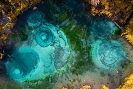 Aerial image showing vivid turquoise geysers in mineral-rich water surrounded by scenic natural vegetationの写真素材