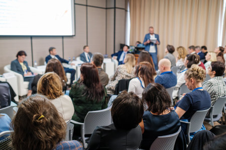 Attendees sit in audience, participating in a seminar with speakers discussing professional topics.の写真素材