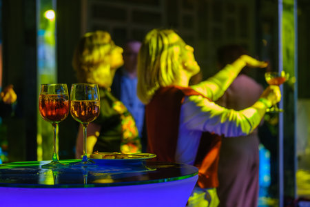Vibrant party atmosphere with people enjoying drinks at an illuminated table, showcasing excitement and celebration.の写真素材