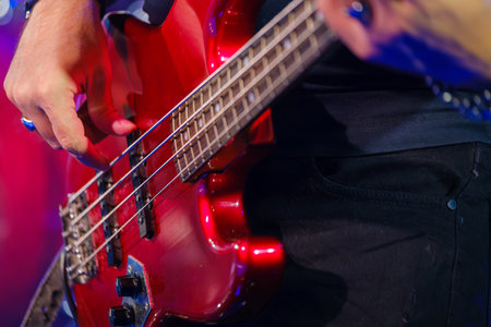 Musicians hand with rings playing electric bass guitar on stage, emphasizing passion for live music performance.の写真素材