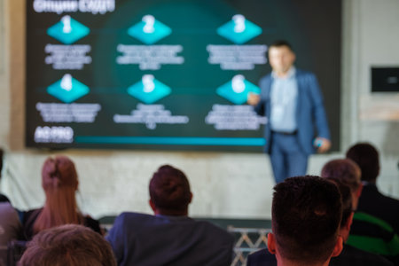 Professional business presentation with speaker and audience in a modern conference setting. Engaged audience listens to the speaker sharing insights on screen.の写真素材