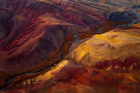 Aerial view showing an autumn-toned mountain landscape, vivid red colors, and a winding river.の写真素材