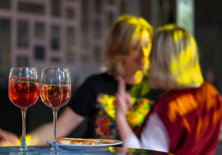 Two glasses of rose wine on table with friends in background celebrating summer evening outdoors.の写真素材