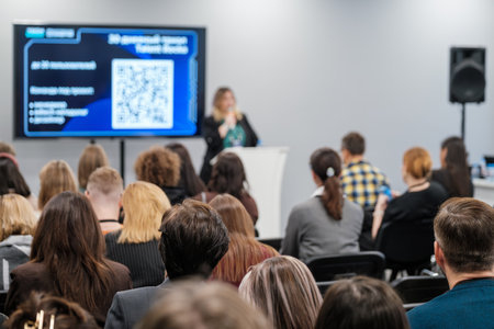 Business professional delivering presentation at conference. Diverse audience listening attentively to speech.の写真素材