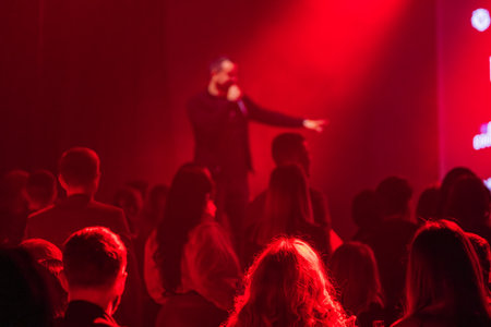 Performing artist interacting with crowd in vivid red lighting creating dynamic atmosphereの写真素材