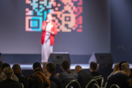 Blurred background featuring speaker on stage presenting to audience during corporate event