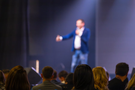 Presenter speaking on stage with blurry focus, addressing audience in a conference setting.の写真素材