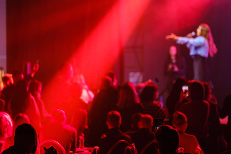 Energetic live music performance with crowd enjoying under red lights in a nightclub settingの写真素材