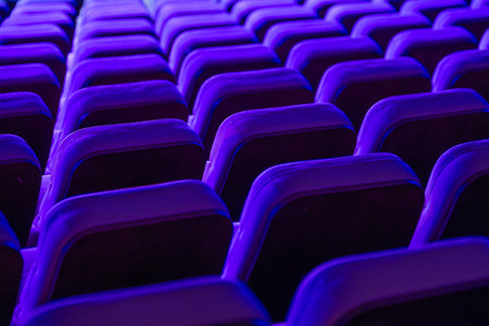 Vibrant rows of theater seats illuminated by purple lights, showcasing repetitiveness and symmetry.