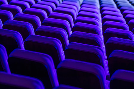 Brightly lit rows of theater chairs in vivid blue hues creating a dynamic abstract scene