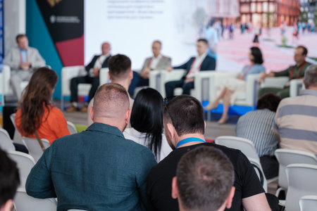People attending conference focusing on expert panel discussion with speakers sharing knowledge and...