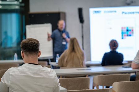 Speaker leading a business presentation with attendees listening in a contemporary meeting room
