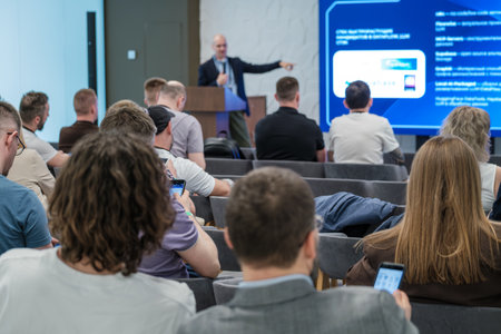 People participating in professional seminar with speaker presenting information using large display...