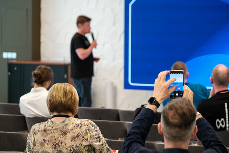 Presenter sharing insights with seated participants at a seminar in an office settingの写真素材