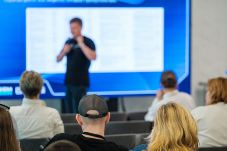 Conference attendees seated while speaker presents at a seminar. Blurred screen background.の写真素材