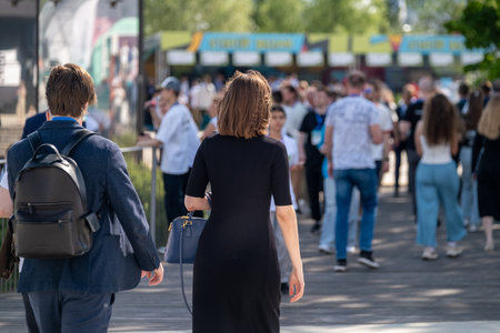 Crowded outdoor venue with attendees walking in sunny weather, socializing, and enjoying. This image captures an active atmosphere with people engaging in various activities during a public gathering.の写真素材