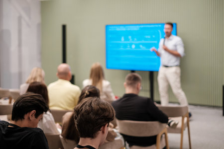 Professional speaker presents topics to attentive audience in a modern, well-lit conference setting.の写真素材