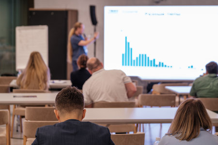 Conference attendees focusing on a speaker presenting data charts during a business seminarの写真素材