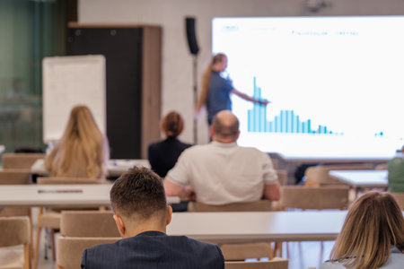 Informative seminar featuring graphs on screen with participants paying attention in meeting venue.の写真素材