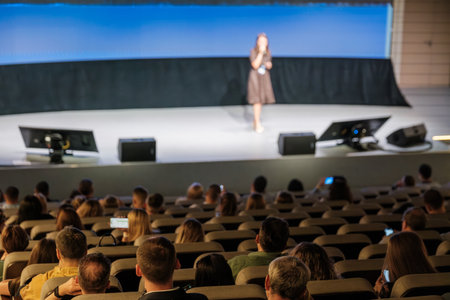 Speaker presenting on stage to audience in large conference setting with a focus on communication.の写真素材