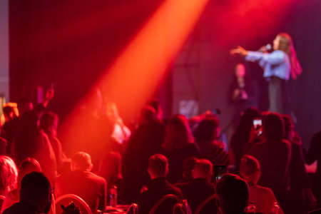 Audience enjoys live performance on stage illuminated by striking red lighting creating dynamic atmosphereの写真素材