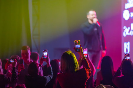Group of people recording a live music event using smartphones while enjoying vibrant atmosphereの写真素材
