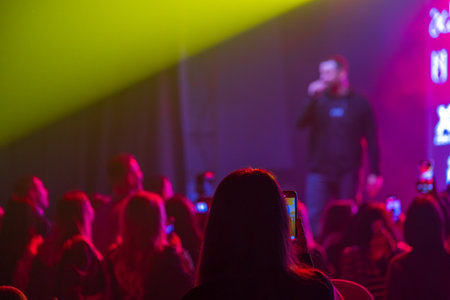 Crowd watching a singer perform on stage under bright lights during an evening concert