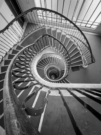 Aerial view spiral staircase monochrome shows looping railings central core conveying motion mystery...