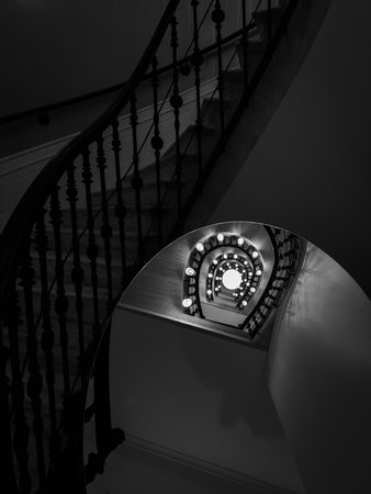 Monochrome spiral staircase with illuminated circular lights along railing creates depth and mysteryの写真素材