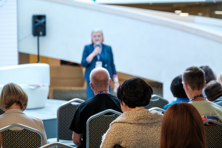 Speaker delivers talk to attentive crowd in bright atrium conference settingの写真素材