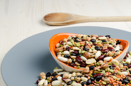 legumes in a dish with spoon close up on wood background