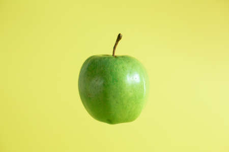 green apple on yellow backgroundの写真素材
