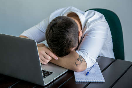 tired young man at work in the officeの写真素材